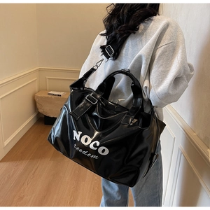 Close-up of black glossy travel bag with white NOCO freedom text and silver buckles