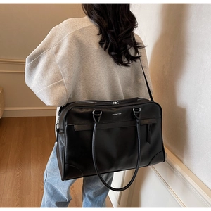 Gros plan du sac de voyage en cuir noir mat avec fermeture éclair et logo argenté
