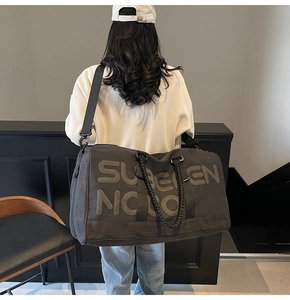 Large capacity dark grey travel bag with woven handles shown being carried on shoulder