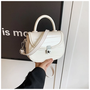 Close-up of cream-colored saddle bag with striped texture and silver twist lock detail