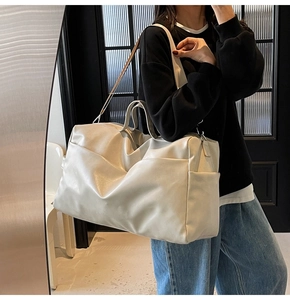 Vista laterale della borsa tote in pelle crema con grande capacità e tracolla regolabile
