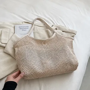 Detail shot of the large beige woven straw beach bag featuring a circular metal buckle