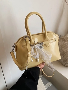 Elegant yellow crossbody bag with pearl bow accessory and metal lock in a soft setting