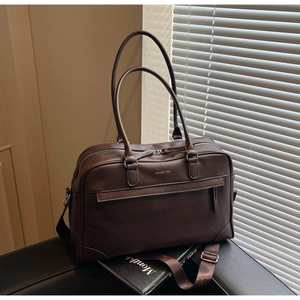 Sac de voyage en cuir marron foncé avec bandoulière réglable et détails métalliques