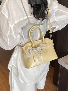 Light yellow PU leather handbag with white lace bow and pearl chain on back of model