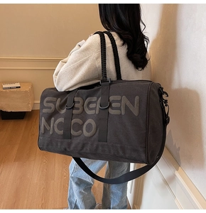 Detail of grey canvas travel bag with 3D embossed lettering and black handles