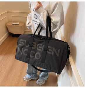 Detailed side view of black travel bag with embossed 3D lettering and woven handles