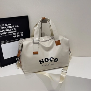 Detail of a cream faux leather travel bag with brown handles and NOCO freedom logo print