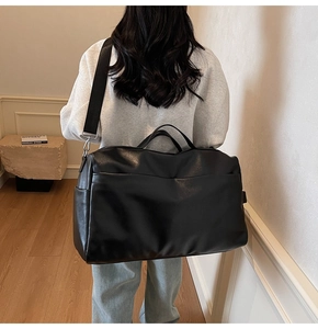 Dettaglio di una grande borsa tote vintage nera con tracolla regolabile su modella