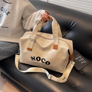 Detail of cream white PU leather travel bag with adjustable strap on a leather sofa