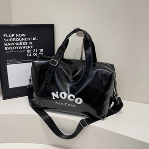 Detail of glossy black travel bag with white NOCO freedom print and silver hardware