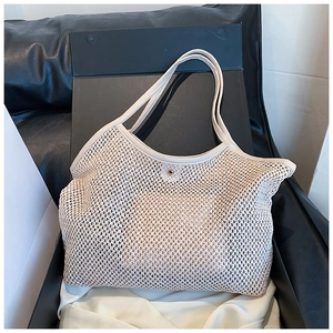 Detail of cream woven tote bag featuring leather trim and a golden buckle closure
