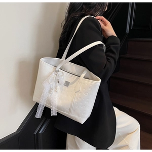 Detailed view of white embossed tote bag with lace bow and pearl charm on a model