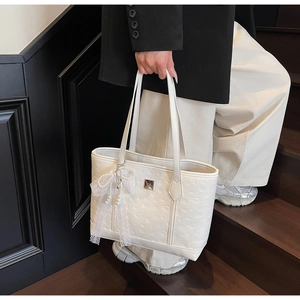 Detail of white embossed leather tote bag with lace bow and pearl pendant charm
