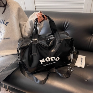Detail of glossy black leather travel bag with white NOCO letter print and metallic clips
