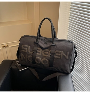 Detailed close-up of charcoal canvas travel bag with woven handles on leather seat