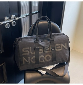 Close-up of charcoal travel bag with embossed logo on modern leather chair