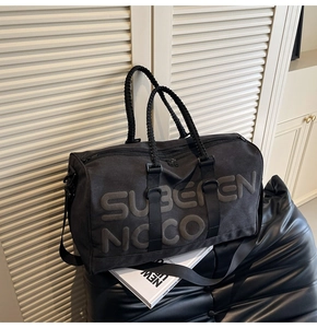 Close-up of embossed text on black travel bag with reinforced woven handles