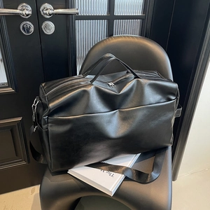 Dettaglio della grande borsa tote nera in pelle con doppi manici e tracolla rimovibile