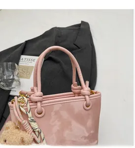 Detail of pink patent leather bucket bag featuring a knot handle and plush bear charm
