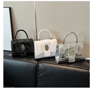 Detail of three textured leather mini square bags in black, white, and silver colors