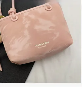 Detailed view of pink suede bucket bag with gold lettering and soft knotted handle