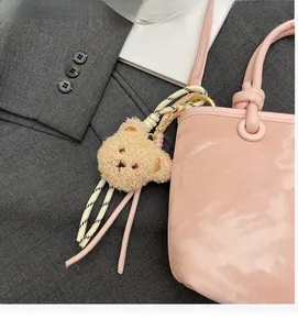 Detail of plush bear bag charm with woven ropes on a pink leather bucket bag
