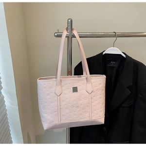 Close-up of pink tote bag with embossed cartoon puppy patterns and a square metal logo plate