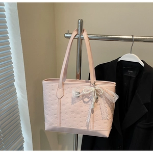 Detail of pink embossed tote bag featuring elegant lace bow and pearl bead accents