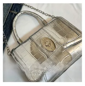 Close-up of silver crocodile pattern texture and metallic oval twist lock on handbag