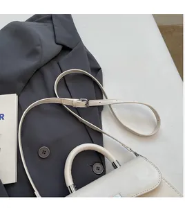 Detail of cream crossbody bag with adjustable long shoulder strap and silver metal buckle