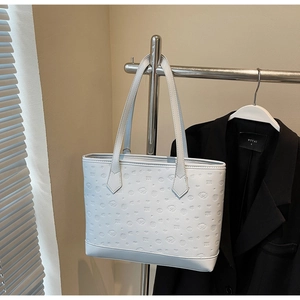Close-up of white tote bag featuring embossed cartoon dog patterns and sturdy handles