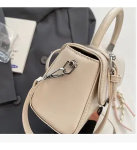 Detail of cream white glossy leather handbag featuring premium silver metal hardware