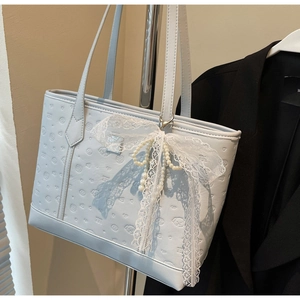 Close-up of light blue tote bag featuring dog embossing and a lace bow with pearls