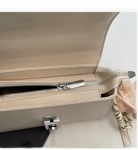 Top view of cream leather handbag showing smooth silver zipper and metal rotary lock detail