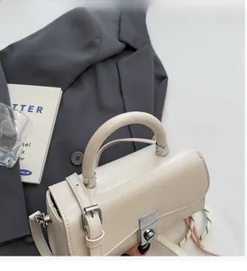 Detail of a chic cream leather bucket bag with silver metal buckle on a grey blazer