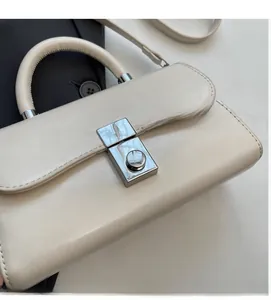 Detailed close-up of the silver metal lock and buckle on a cream faux leather handbag