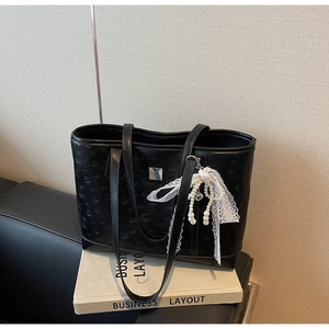 Detail of black embossed leather tote bag with silver buckle and pearl lace charm