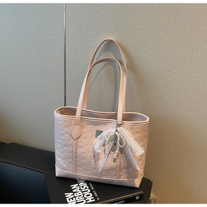 Detailed view of pink tote bag with embossed pattern and pearl lace bow charm