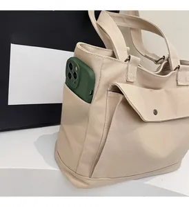 Detail view of large canvas tote bag showing side pocket capacity with a smartphone