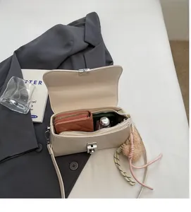 Top view of spacious cream crossbody bag interior with woven rope charm detail