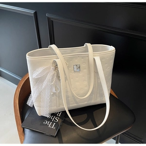 Detailed view of white tote bag with heart embossing and lace pearl bow ornament