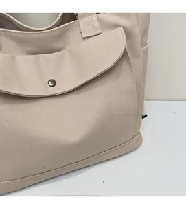 Close-up of canvas tote bag showing metal snap button closure and side pocket detail