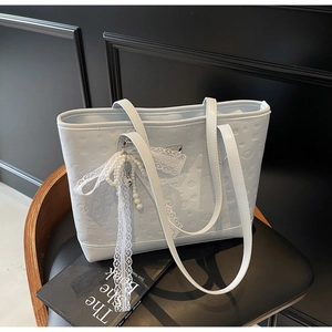 Detail of light blue tote bag with embossed textures and a lace bow pearl charm