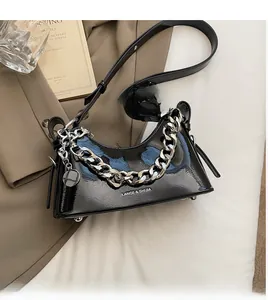 Detail of black patent leather baguette bag with thick silver chain on suit fabric