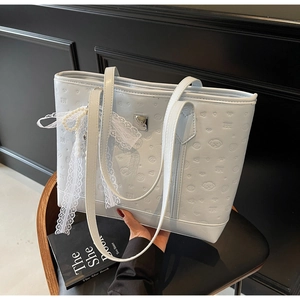 Detail of light blue leather tote bag with embossed patterns and pearl bow charm