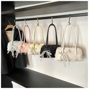 Detail of five marble texture Boston bags with lace bows and pearl pendants hanging in a closet