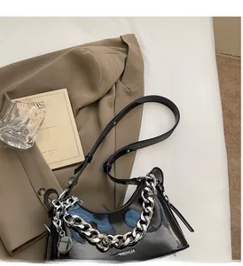 Detail of glossy black crescent bag with chunky silver chain and leather strap