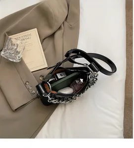 Detail view of the spacious interior of a glossy black underarm bag with silver chain