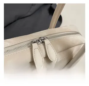 Detailed macro view of the silver metal zipper and stitching on the beige Boston bag